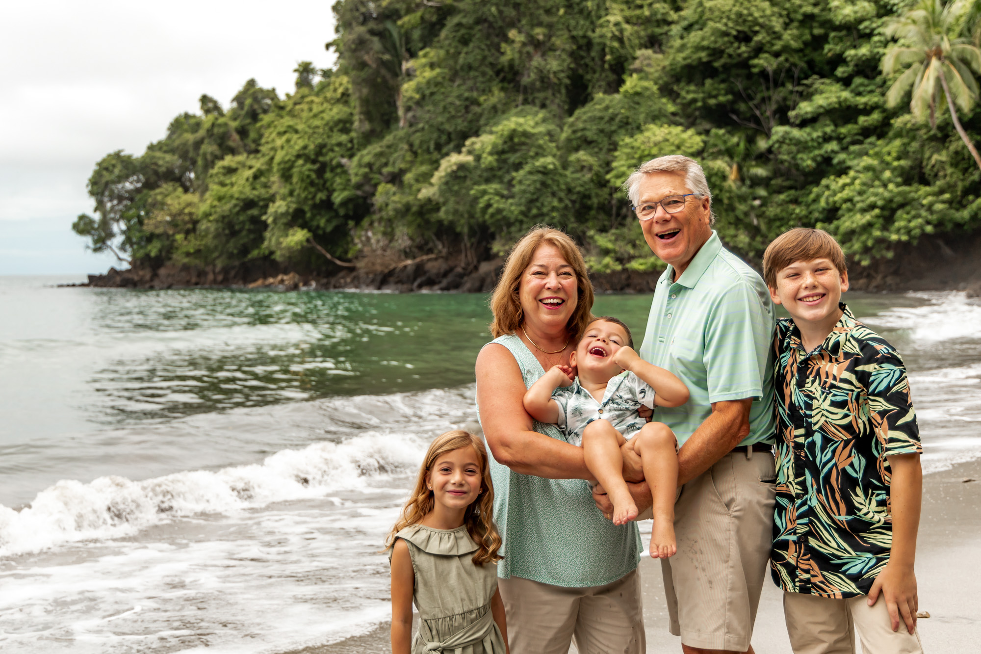Girl looking whimsical in front of a leafy green bush